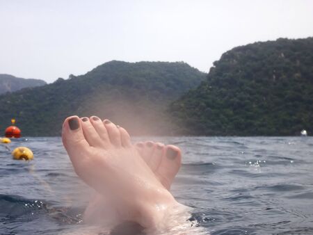 Sea surface with buoys, woman legs under water and mountains in the distance. View and shooting from...