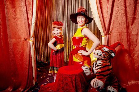 Family during a stylized theatrical circus photoshoot in a beautiful red location. Models mother and...