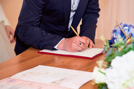 Russia, Kirov - March 22, 2019: Wedding and marriage registration at the registry office. Bride and groom sign the document on the table in hall for ceremonyのeditorial素材