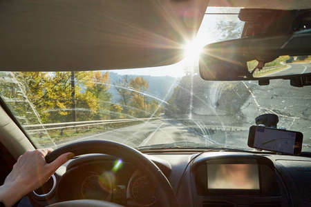 Tbilisi, Georgia - October 22, 2019: Car vindow, hand of woman on steering wheel and view to the road and autumn mountain landscape in a sunny day. Concept alone travel to nature during coronavirusのeditorial素材