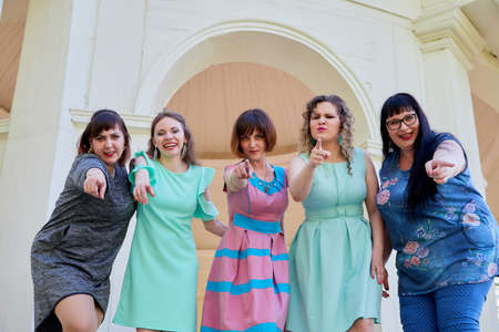 Group of female friends in the white gazebo among the columns. Women and adult girl have fun together outdoorのeditorial素材