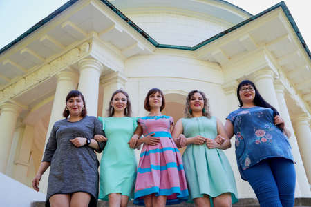Group of female friends in the white gazebo among the columns. Women and adult girl have fun together outdoorのeditorial素材