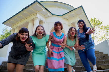 Group of female friends in the white gazebo among the columns. Women and adult girl have fun together outdoorのeditorial素材