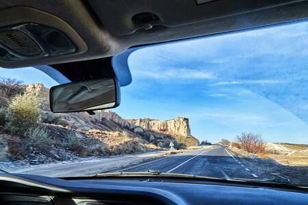 View from car window on the road and strange landscape with a valley, mountains and blue sky with clouds. Landscape through windscreen in Cappadocia at Turkeyの写真素材