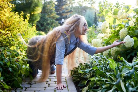 Pretty teenage girl 14-16 year old with curly long blonde hair in the green park in a summer day. Beautiful outdoors portraitの写真素材