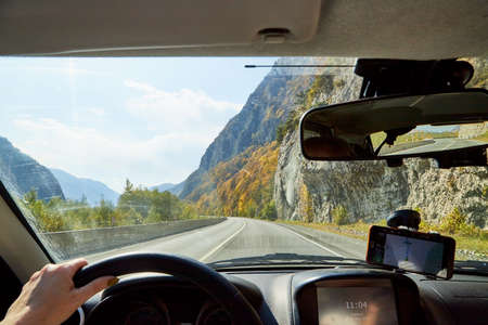 Tbilisi, Georgia - October 19, 2019: View from inside car window to the road and autumn mountain landscape. Asphalt road in perspective in a sunny day. Concept alone travel to nature during covid-19のeditorial素材