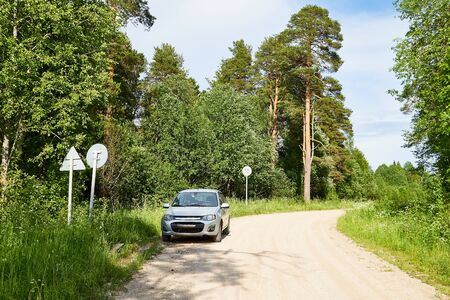 Car on an old road on summer day in forest. Nature landscape with green trees and blue sky in a...