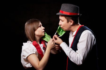 Loving couple in national traditional ethnic dress in green sterile medical face masks on a black background. Girl and man kissing during quarantine of COVID-19 coronavirus pandemic. Virus conceptの写真素材