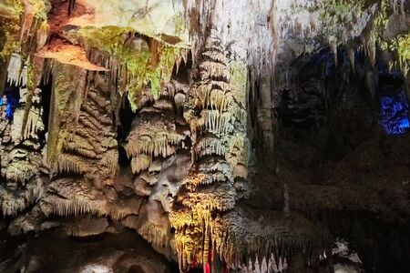 Beautiful colorful and illuminated cave with stalactites and stalagmites and black backgroundの写真素材