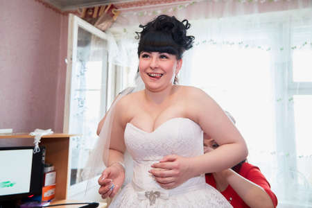 Russia, Kirov - March 22, 2019: Bridesmaids helping to bride to dress wedding white dress before wedding and marriage registration at homeのeditorial素材