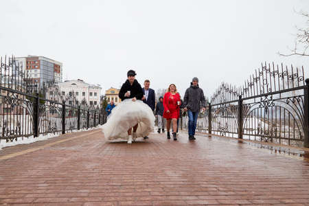 Kirov, Russia - March 22, 2019: Bride and groom walking with group of young friends on the street of city on a cold winter or autumn day in Russiaのeditorial素材