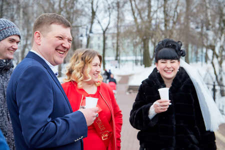 Kirov, Russia - March 22, 2019: Bride and groom walking with group of young friends on the street of city on a cold winter or autumn day in Russiaのeditorial素材