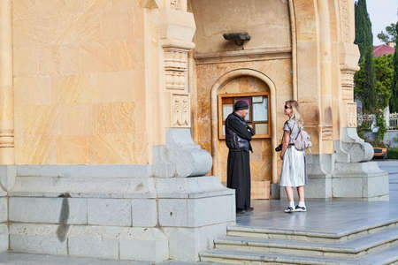 Tbilisi, Georgia - October 21, 2019: Big orthodox cathedral St. Trinity or Chirch Sameba and a girl with a priest near the entrance in Tbilisi city in Georgiaのeditorial素材