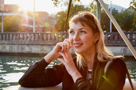Portrait of young caucasian girl relaxing near water of river and promenade background in a sunny summer, spring or autumn nice dayの写真素材