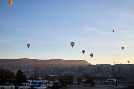 Cappadocia, Turkey - December 20, 2019: Hot air balloons flying in blue sky with white clouds over rock landscape at morning during sinrise. Great interesting attraction for tourists in Goremeのeditorial素材