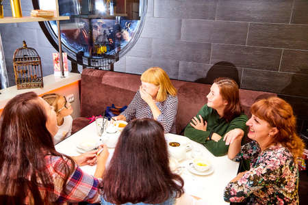 Kirov, Russia - September 17, 2019: People at table in small cafe or restaurant during intellectual game. Hungry group waiting for the waiter to get the menu or foodのeditorial素材