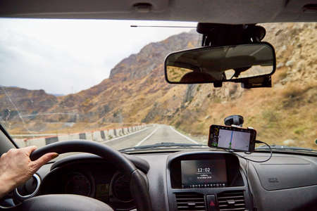 Tbilisi, Georgia - October 19, 2019: View from inside car window to the road and autumn mountain...