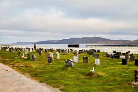 Warde, Norway - June 23, 2019: Graveyard and old tombstones that sits in a field of green grass and cloudy sky backgroundのeditorial素材
