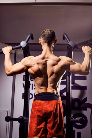 Handsome young male bodybuilder in the gym. Big strong man during training in the gym. Guy with big...