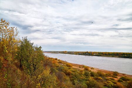 View on the river from top place on the bank through branch of trees and sky with clouds background.. Nature landscape in a summer or autumn dayの写真素材