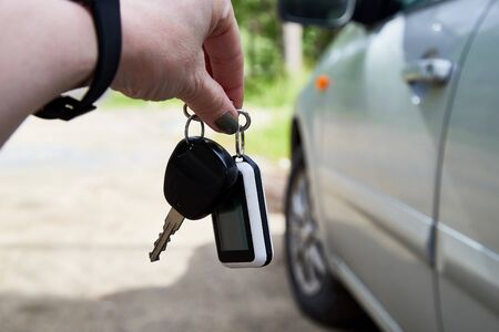 Hand of woman holding car key near carの写真素材