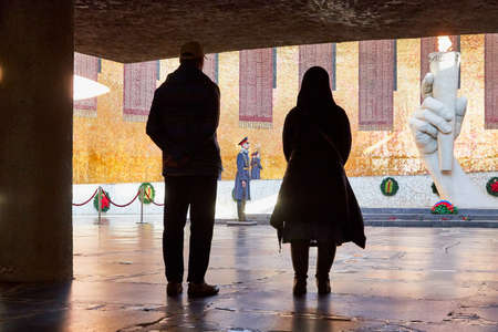 Volgograd, Russia - October 18, 2019: Tourists in Hall of Military Glory in Memorial complex Mamayev Kurgan. Sculpture of hand holding torch with Eternal Fire. Eternal Fire is guarded by soldiersのeditorial素材