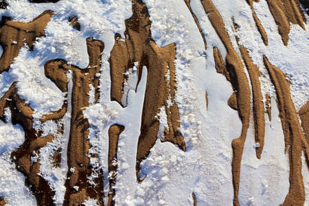 Testure or background with snow, ice and sand in a cold winter day outdoors. Nature landscape with frozen snow on a sandy beach or coast of lake or river in the cold and sun.の写真素材