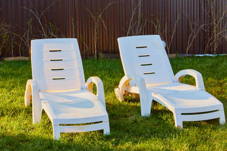 White sunbed in the garden with small house. Conctpt of summer rest outdoors