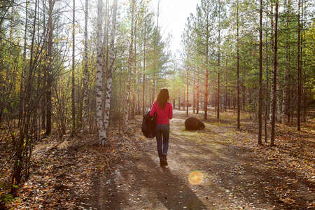 Beautiful young woman walking in the forest with sprice in autumn day