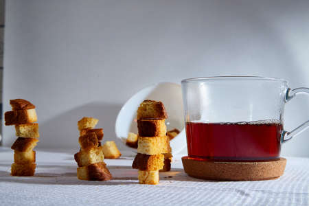 Square toasted pieces of homemade delicious rusk, hardtack, Dryasdust, zwieback stand in columns near white plate on a white tableclothの写真素材