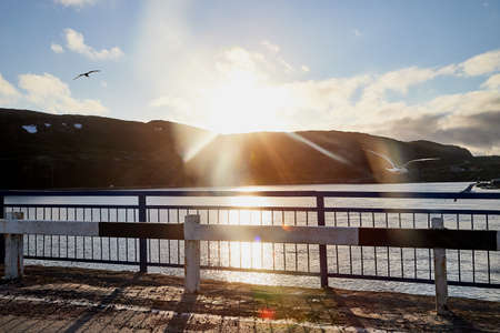 View on railing of bridge and water of river below. Sun from hills in nature landscape in the evening or during the day. Concept of travel and tourismの写真素材