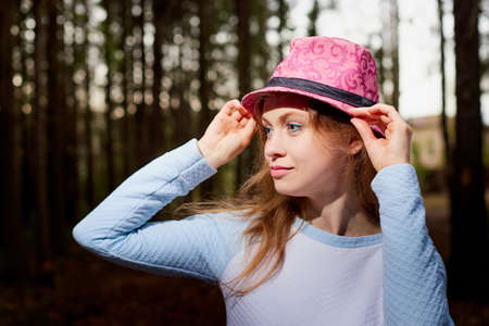 Portrait of cute blonde girl walking in forest outdoors. Nice woman posing on nature landscape with pine treesの写真素材