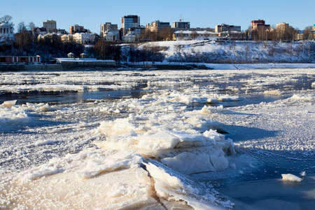 Ice on the river on a Sunny winter day and city on background. Ice texture and backgroundの写真素材