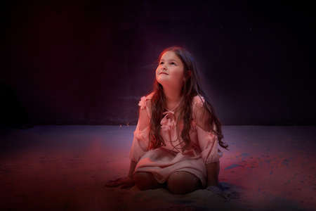 Small girl in white dress in dark studo during photoshoot with flour.の写真素材