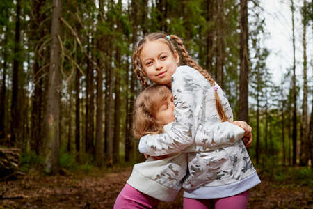 Two young girl playing and having fun together on walk in forest outdoors.の写真素材