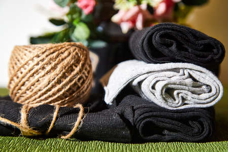 Several pairs of new male cotton socks on a green surface, skein of thread and flowers background....