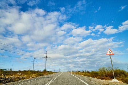 View from car windscreen with stripe relief to highway, tundra and blue sky in norht region at a...