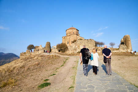 Mtskheta, Georgia - October, 25, 2019: Orthodox church in Jvari Monastery located near Mtskheta, Georgia. Old house built of yellow stones and bricks on the hill and tourist near it during travelのeditorial素材
