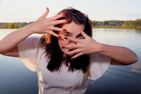 Portrait of the girl or woman on the shore or beach of the lake in the evening at sunsetの写真素材