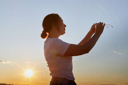 Portrait of the girl or woman on the shore or beach of the lake in the evening at sunset. Sun other waterの写真素材