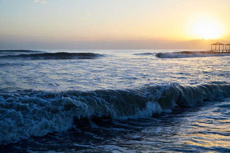 Waves with foam in a water of sea in the evening during sunsetの写真素材