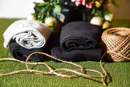 Several pairs of new male cotton socks on a green surface, skein of thread and flowers background....