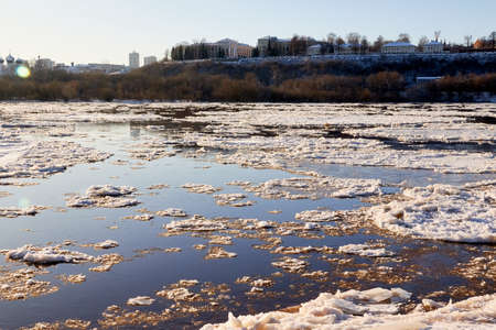 Ice drift on a river with blue high water and big water, white snow broken ice full of hummocks in...