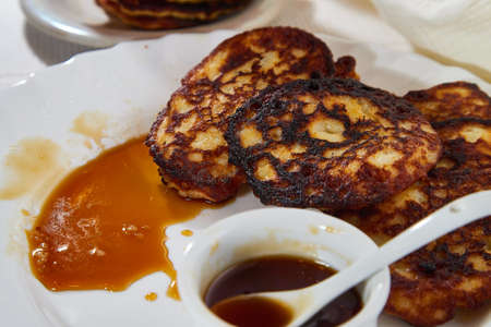 Pancakes on white plate and sweet liquid honey or caramel with a small spoon and with background....