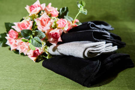 Several pairs of new male cotton socks on a green surface and flowers background. The concept of coziness and comfort. Gift to a manの写真素材