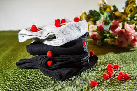 Several pairs of new male cotton socks on a green surface and flowers background. The concept of coziness and comfort. Gift to a manの写真素材