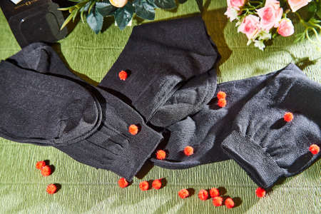 Several pairs of new male cotton socks on a green surface and flowers background. The concept of...
