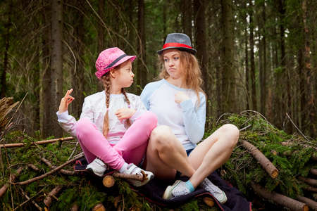 Mother and her child girl playing and having fun together on walk in forest outdoors. Happy loving family posing on nature landscape with with pine treesの写真素材