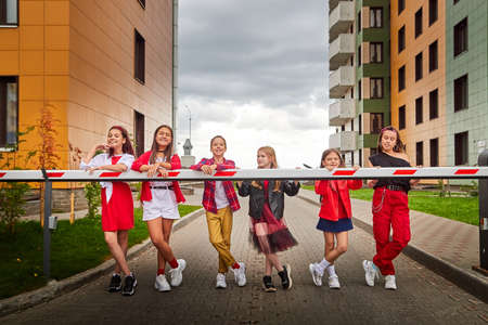 Group of fun children in stylish clothes near big modern house in the city in a summer, spring, or...