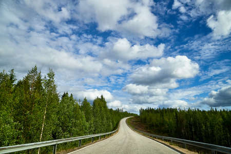 Beautiful landscape with blue sky, white clouds and the road that goes to the horizon with the...